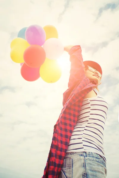 Hand of a teenage girl holding colorful balloons in the sunshine