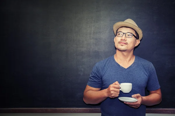 Bir fincan kahve ayakta blackb önünde tutan yakışıklı adam — Stok fotoğraf