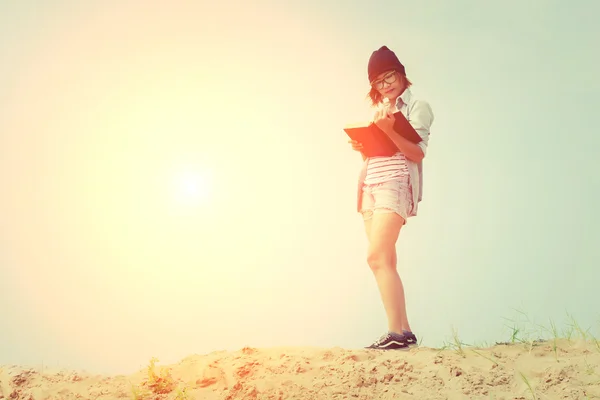 Mulher bonita ler livro de pé na areia olhar tão — Fotografia de Stock