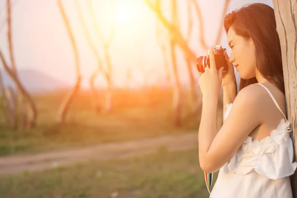 Beautiful young woman shooting with retro camera — Stock Photo, Image