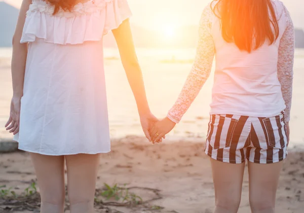 Zwei junge Frauen halten sich am Meer die Hand — Stockfoto