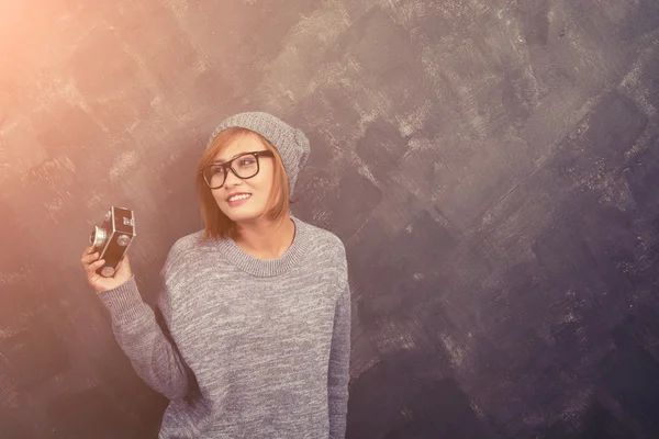 Sonriente mujer hipster con gafas sosteniendo una cámara retro aga —  Fotos de Stock