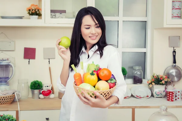 Eszik egy egészséges, zöld alma, a konyhában, és a gyönyörű fiatal nő — Stock Fotó
