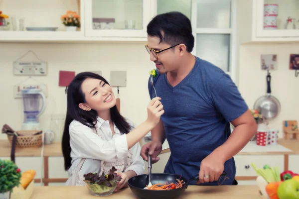 Happy couple Eating vegetable. Having fun in the kitchen. — Stock Photo, Image