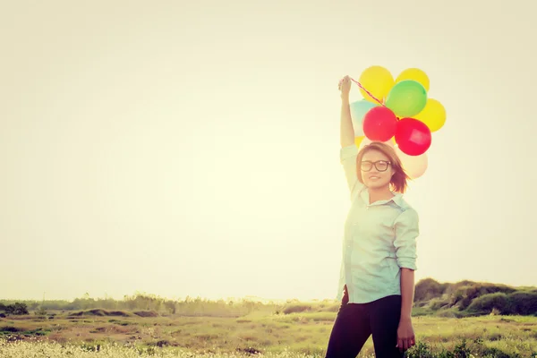 Beautiful young woman standing holding colorful of balloons in t — Stock Photo, Image