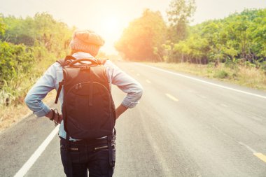 Genç bir kadının kırsal yol walki üzerinde otostop arkadan görünüş