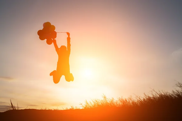 Silhueta de mulher jovem salto segurando colorido de balões sagacidade — Fotografia de Stock
