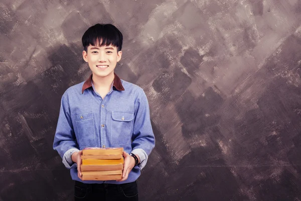 Grunge duvar gülen üzerinde kitap Asya yakışıklı genç — Stok fotoğraf