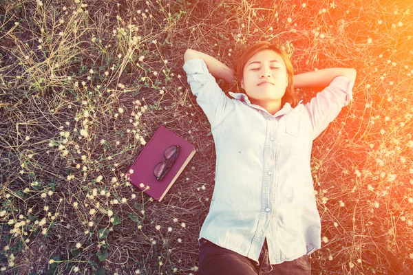 Jonge hipster vrouw liggend in bloem veld nadat ze moe voor re — Stockfoto