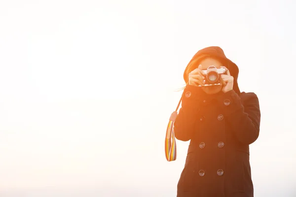 Mujer joven con abrigo negro de pie llevar cámara retro — Foto de Stock