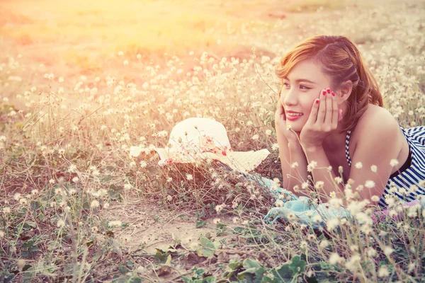 Jonge sexy vrouw rusten op het veld van de bloem en de glimlach — Stockfoto