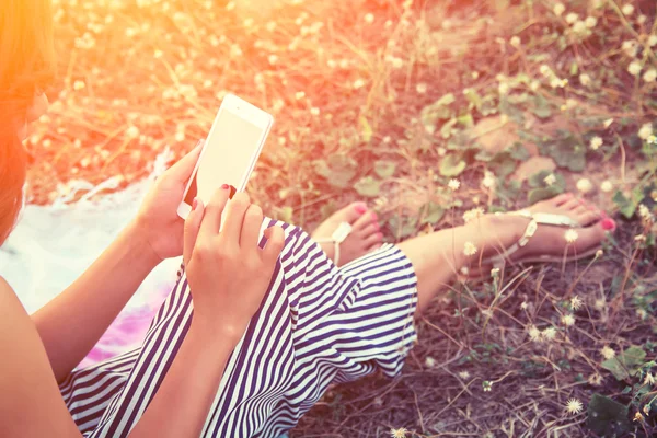 Manos de mujer usando un teléfono inteligente en el campo de flores en verano — Foto de Stock