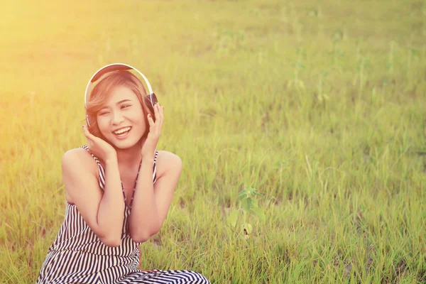 Beautiful sexy woman sitting  listening music from headphone smi — Stock Photo, Image