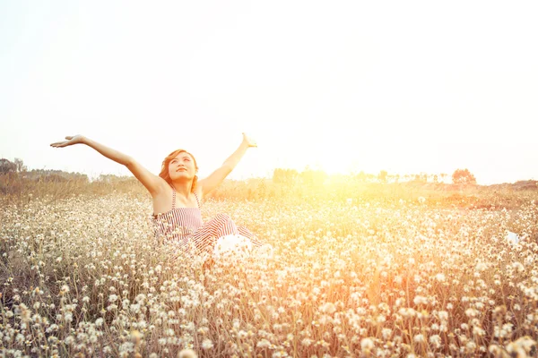 Sexy hermosa mujer sentada en el campo de flores levantando las manos con — Foto de Stock