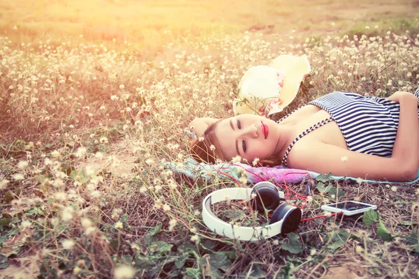 Bella giovane donna sexy sdraiata vicino cuffia nel fiore — Foto Stock