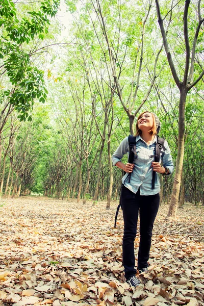 Schöne junge Frau mit Rucksack, die im Wald spazieren geht — Stockfoto