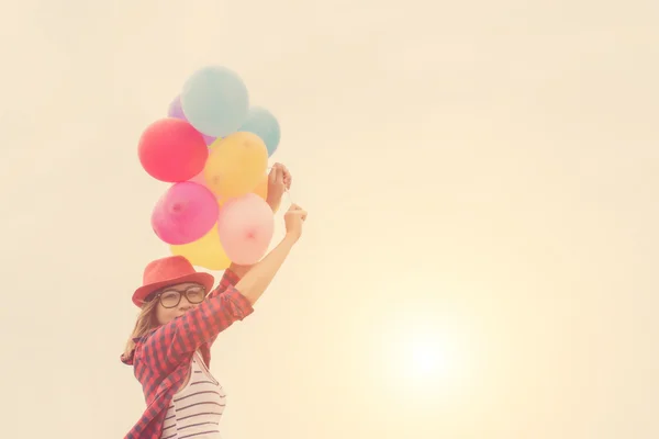 Young hipster girls holding colorful balloons in the bright sky — Stock Photo, Image