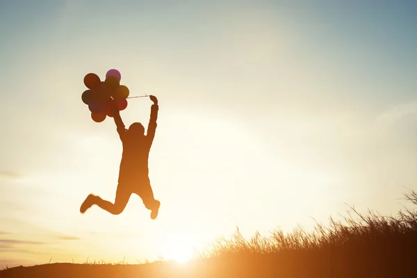Jovem com balões pulando ao ar livre — Fotografia de Stock