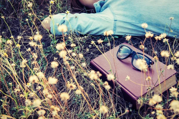 Vintage style of retro camera with book and glasses in the flowe