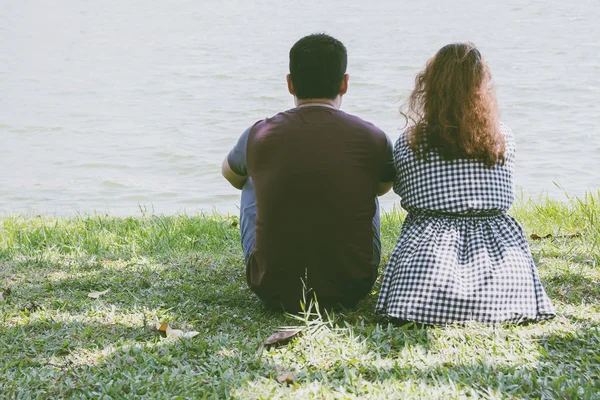 Young couple sitting near the lake. — Stock Photo, Image