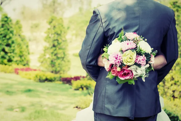 Braut umarmt Bräutigam und ihre Hände halten Blumenstrauß in Hochzeitsgesellschaft. — Stockfoto