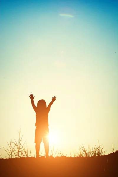 Silhueta de menina levantar as mãos com o pôr do sol . — Fotografia de Stock