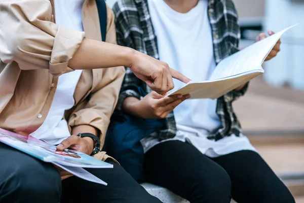 Male and female students wearing masks sit and read books on the stairs