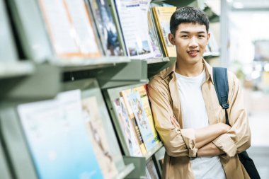 Sırt çantası taşıyan ve kütüphanede kitap arayan adamlar..