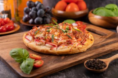 Biber tohumlarıyla dolu tahta bir tabağa yerleştirilmiş pizza. Domates ve sarımsak. Seçici odak.