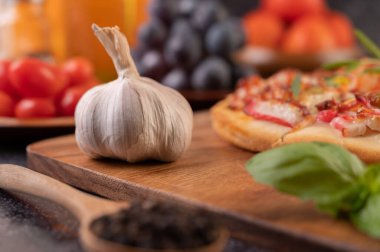 Tahta kesme tahtasında sarımsak, fesleğen, biber tohumu. Seçici odak.