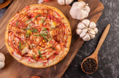 Biber tohumlarıyla dolu tahta bir tabağa yerleştirilmiş pizza. Domates ve sarımsak. Üst görünüm.
