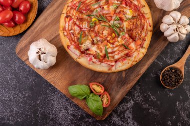 Biber tohumlarıyla dolu tahta bir tabağa yerleştirilmiş pizza. Domates ve sarımsak. Üst görünüm.