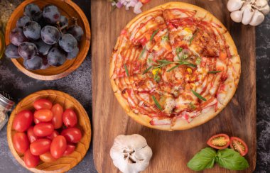 Biber tohumlarıyla dolu tahta bir tabağa yerleştirilmiş pizza. Domates ve sarımsak. Üst görünüm.