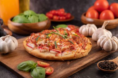 Biber tohumlarıyla dolu tahta bir tabağa yerleştirilmiş pizza. Domates ve sarımsak. Seçici odak.