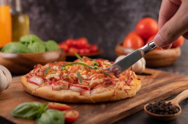 Biber tohumlarıyla dolu tahta bir tabağa yerleştirilmiş pizza. Domates ve sarımsak. Seçici odak.
