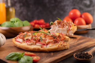 Biber tohumlarıyla dolu tahta bir tabağa yerleştirilmiş pizza. Domates ve sarımsak. Seçici odak.