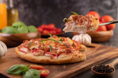 Biber tohumlarıyla dolu tahta bir tabağa yerleştirilmiş pizza. Domates ve sarımsak. Seçici odak.