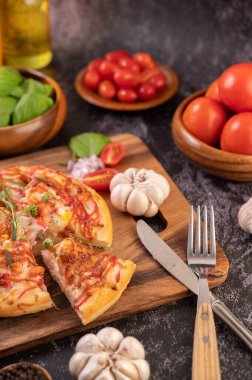 Biber tohumlarıyla dolu tahta bir tabağa yerleştirilmiş pizza. Domates ve sarımsak. Seçici odak.