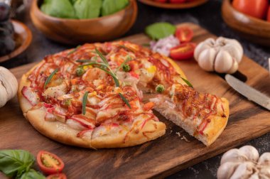 Biber tohumlarıyla dolu tahta bir tabağa yerleştirilmiş pizza. Domates ve sarımsak. Seçici odak.