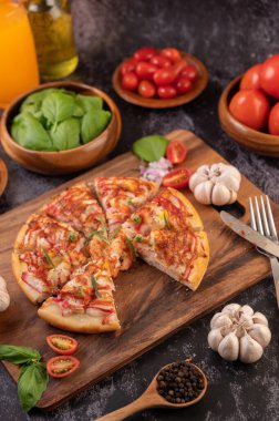Biber tohumlarıyla dolu tahta bir tabağa yerleştirilmiş pizza. Domates ve sarımsak. Seçici odak.