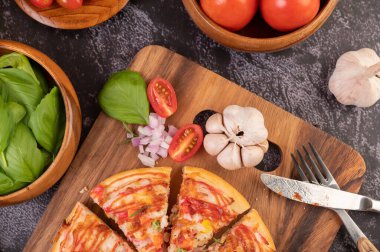 Biber tohumlarıyla dolu tahta bir tabağa yerleştirilmiş pizza. Domates ve sarımsak. Üst görünüm.