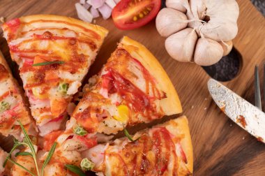 Biber tohumlarıyla dolu tahta bir tabağa yerleştirilmiş pizza. Domates ve sarımsak. Üst görünüm.