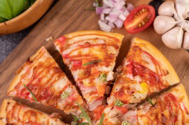 Biber tohumlarıyla dolu tahta bir tabağa yerleştirilmiş pizza. Domates ve sarımsak. Seçici odak.