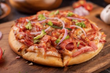 Biber tohumlarıyla dolu tahta bir tabağa yerleştirilmiş pizza. Domates ve sarımsak. Seçici odak.