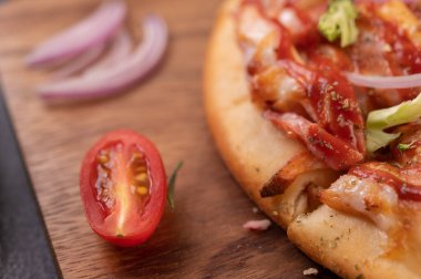 Biber tohumlarıyla dolu tahta bir tabağa yerleştirilmiş pizza. Domates ve sarımsak. Seçici odak.