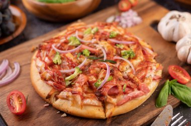 Biber tohumlarıyla dolu tahta bir tabağa yerleştirilmiş pizza. Domates ve sarımsak. Seçici odak.