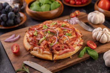 Biber tohumlarıyla dolu tahta bir tabağa yerleştirilmiş pizza. Domates ve sarımsak. Seçici odak.