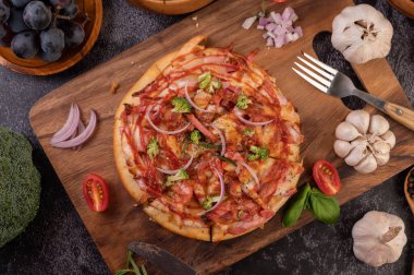 Biber tohumlarıyla dolu tahta bir tabağa yerleştirilmiş pizza. Domates ve sarımsak. Üst görünüm.