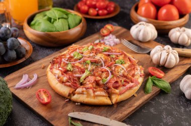 Biber tohumlarıyla dolu tahta bir tabağa yerleştirilmiş pizza. Domates ve sarımsak. Seçici odak.