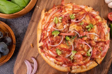 Biber tohumlarıyla dolu tahta bir tabağa yerleştirilmiş pizza. Domates ve sarımsak. Üst görünüm.